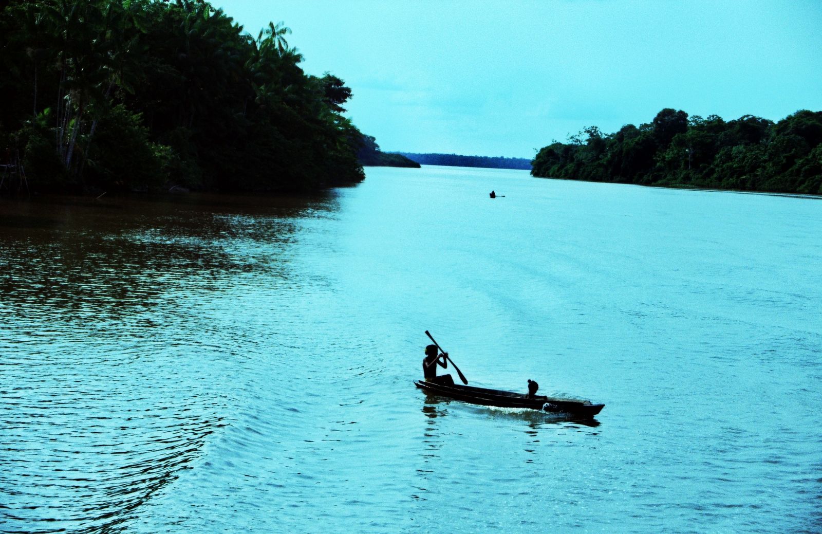 A lone paddler crossing the river at dusk